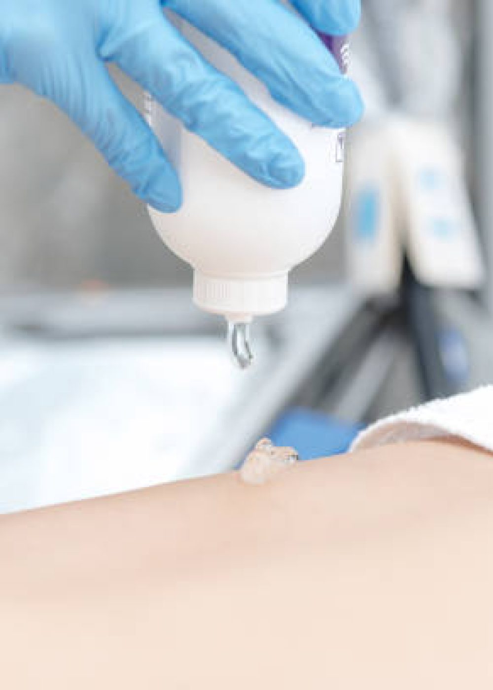 Close-up of a beautician applying laser hair removal gel to a client's legs.